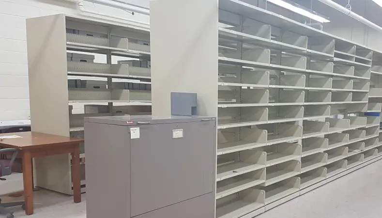Photo shows two rows of empty shelving in the archival storage area in 2380 Lancaster