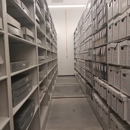 Photo shows new shelving filled with archival boxes in the Ingenium Centre - an environmental sensor is visible on the wall in between the rows of shelving.