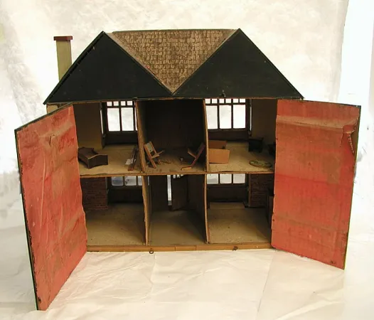 A six-room cardboard dollhouse on a wooden base that opens at the back 