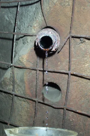 L’eau dégoutte d’un tuyau installé dans la roche sous le sol.