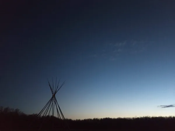 A tipi in the distance at sunset.