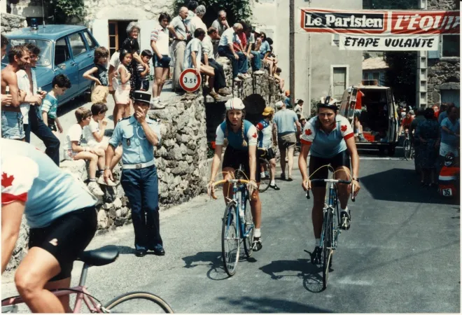 Two female cyclists pedal through a tight roadway during the Tour de France féminin, 1984.