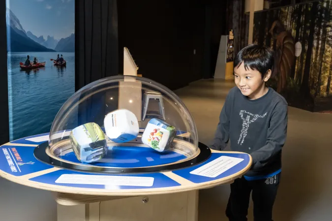 A young smiling child plays an interactive game in the museum's Climate Quest exhibition.