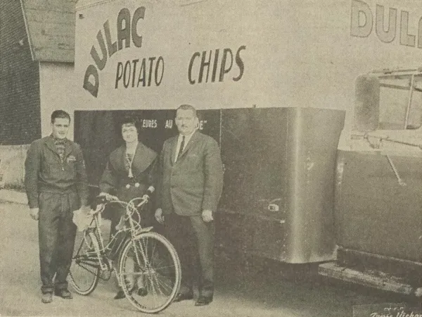 A smiling Mrs. Élie Fortin of Montmagny, Québec, accepting the bicycle won by her daughter, Michèle Fortin, in a contest organised by Dulac Potato Chips Incorporated of Sainte-Marie, Québec. Anon., “–.” Le Peuple, 10 May 1963, 10.