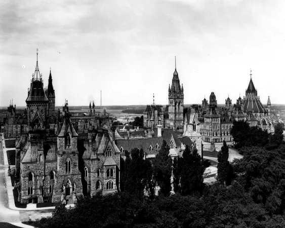 A black and white photograph showing a group of gothic construction stone buildings, with spires and triangular rooves.
