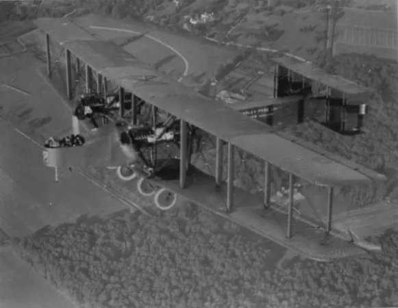 L’image est une photo noir et blanc montrant un avion Handley Page V/1500 en vol. La photo pourrait être une photographie composite. En bas, on voit des champs.