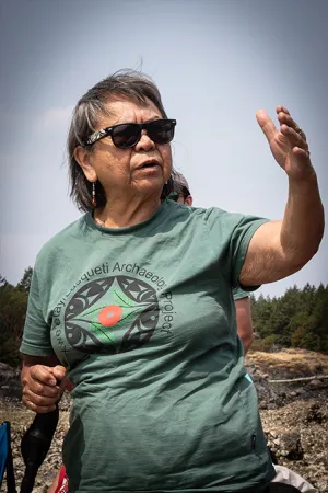 Candid photograph of a woman wearing a green t-shirt, raising her hand in conversation.