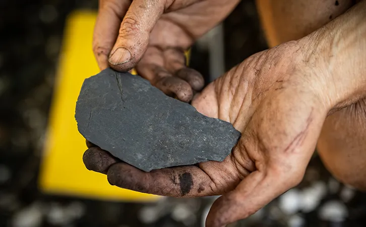 Photograph of hands holding a rock. 