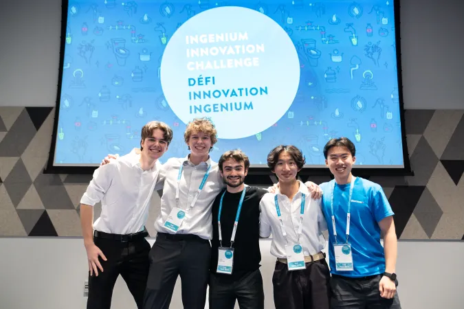 Les cinq participants de l'équipe gagnante devant un panneau avec les mots Defi Innovation Ingenium.