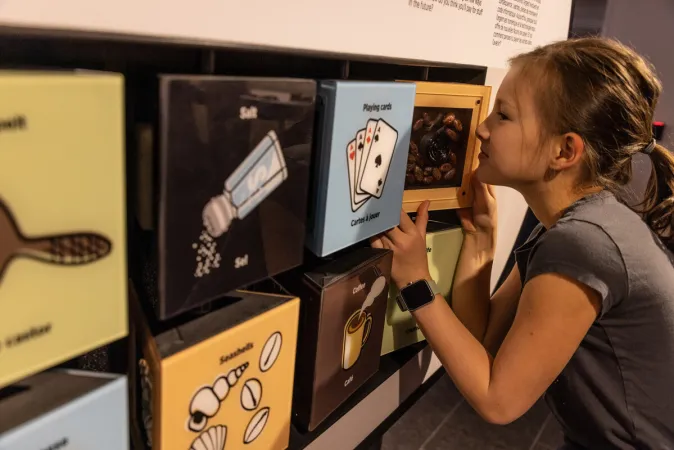 A child leans in to sniff cocoa beans as part of a rotating block interactive.