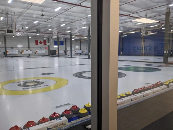 On voit des cercles multicolores sur une surface de glace sur une piste de curling intérieure. Les drapeaux canadien et albertain sont visibles en arrière-plan. 