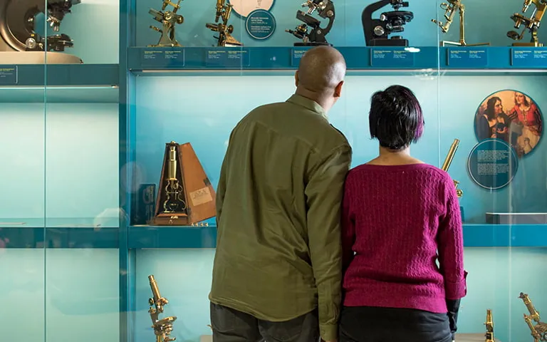 A man and a woman looking at a collection of microscopes