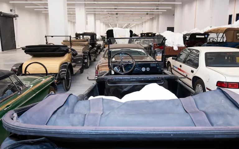 A bright storage room filled with old cars.
