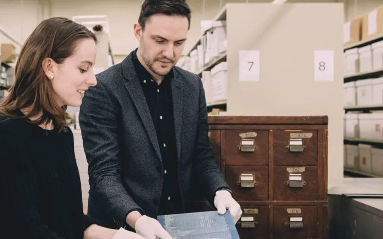 Researchers examine a blueprint in the archival collection
