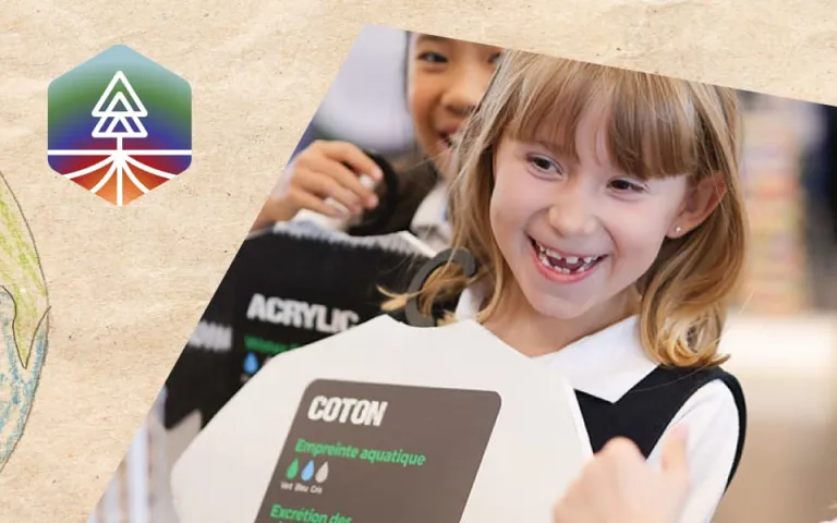 A photo of a smiling child with shoulder length blonde hair holding up a wooden t-shirt that says "cotton." In the photo you can see two other smiling children, one partly in the foreground and a another in the background. The photo is on top of craft paper and on the bottom left there is a hand-drawn picture of the Earth, and on the top left there is a colourful logo of a pine tree with roots.