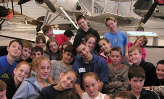 Un groupe d'enfants d'âge scolaire souriants pose devant un avion blanc.