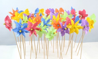 A group of colourful pinwheels on wooden dowels stick out of a large square of white styrofoam.
