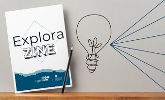 La couverture bleue et blanche d’un zine est présentée sur une tablette avec un crayon. On peut lire les mots « Explora ZINE ». Une illustration artistique d’une ampoule émettant des rayons est juste à côté. 