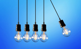 Five light bulbs hang in front of a blue background. The one furthest to the right hangs at a 25⁰ right of the vertical.