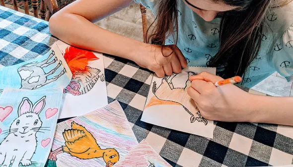 jeune fille qui colore les illustrations d'animaux de la ferme