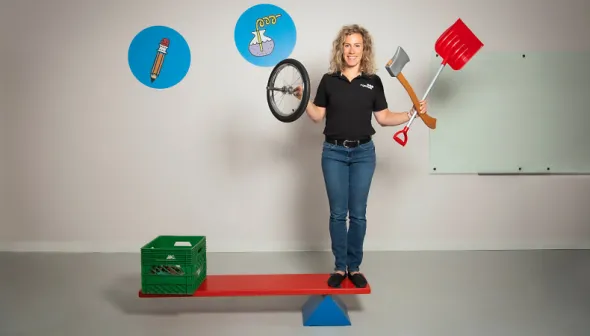 A museum employee showing the functionality of a simple machine while holding other simple machines