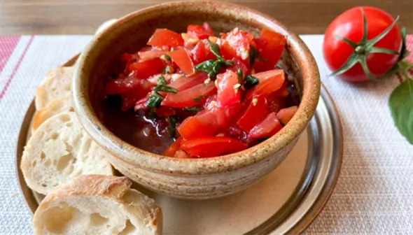 Bowl of bruschetta accompanied by slices of baguette