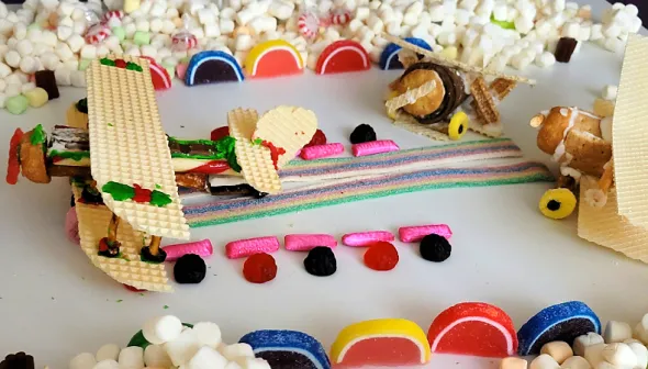 Une table remplie de friandises. Au centre, petits avions faits de biscuits, de glaçage et de bonbons.
