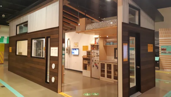 The tiny house at the Canada Science and Technology Museum from the exterior. Parts of the walls are missing to show the small kitchen and loft bed inside.