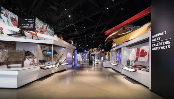 Une vue de l'allée des artefacts depuis l'avant du Musée des sciences et de la technologie du Canada. On peut voir des artefacts le long des murs de l'allée, notamment des canots, un drapeau canadien, un traîneau et une motoneige.
