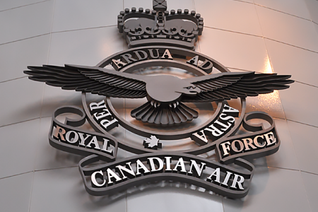 Metal emblem of the Royal Canadian Air Force. The emblem has a crown at the time, at the top and a bird with outstretched wings in the middle.  The words 'Royal Canadian Airforce Per Ardua Ad Astra' are inscribed.