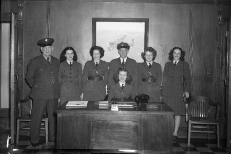 Groupe d'hommes et de femmes en uniforme derrière un bureau