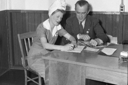 Femme au comptoir signant un papier pour l'achat d'une Obligation de la victoire
