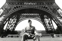 A man in uniform sits in front of the Eiffel Tower.