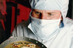 a scientist in clean-room clothing holding a CCD sensor that was installed on the Hubble Space Telescope