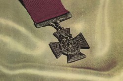 This photo shows the cover of a booklet with Victoria Cross in the center on a background of white silk and the letter V C in red at the bottom.