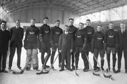 A black-and-white image of team of young hockey players, posing on the ice with their hockey sticks.