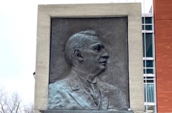 A bronze relief bust of a man is set in stone.